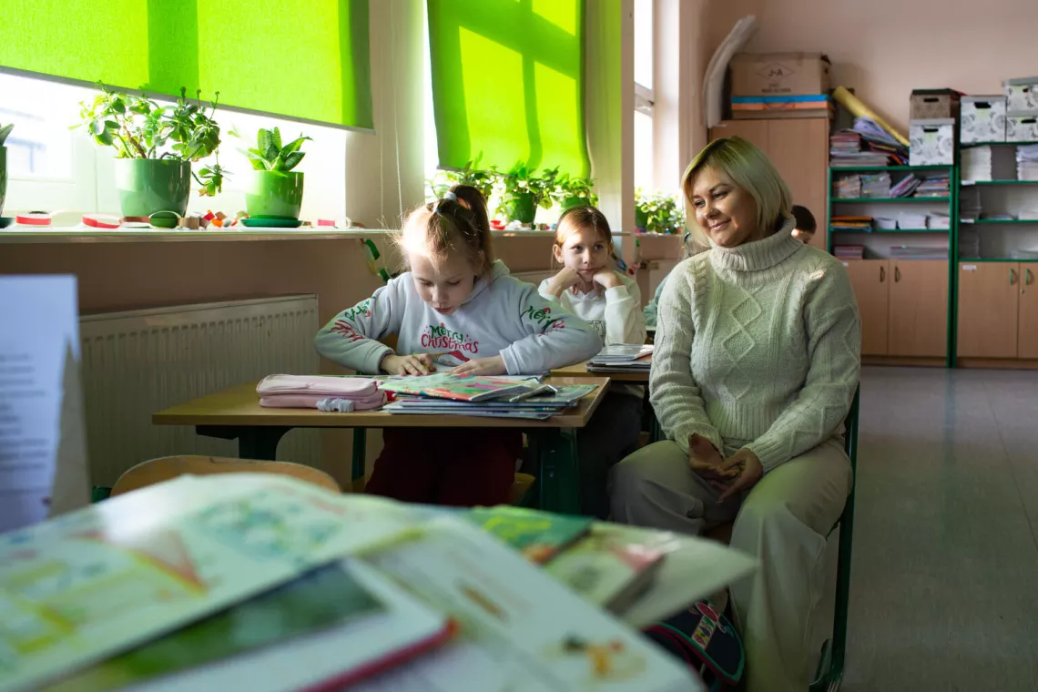 Students work with a teacher in a classroom in Poland