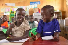 Young children have a light moment during a classroom session at a UNICEF-supported child friendly space in Adjumani District.