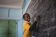 A student laughs as he writes the answers to questions on the chalkboard of his classroom in his UNICEF-supported primary school, Salaama in Galkayo, Somalia, Wednesday, April 12, 2017.